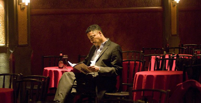 Black man sitting alone in a room with red tables