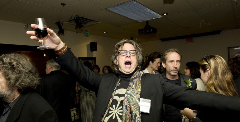 Man with glass of wine and arms open