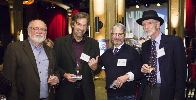 Four middle-aged men smiling at the camera