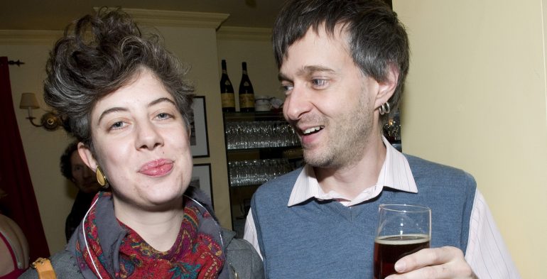Woman smiling into camera and man smiling at woman