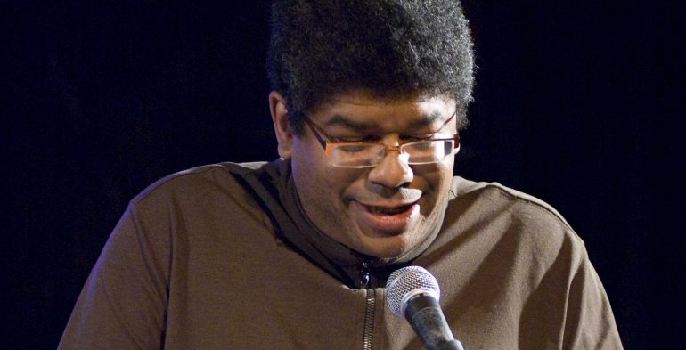 Man of colour reading at a podium