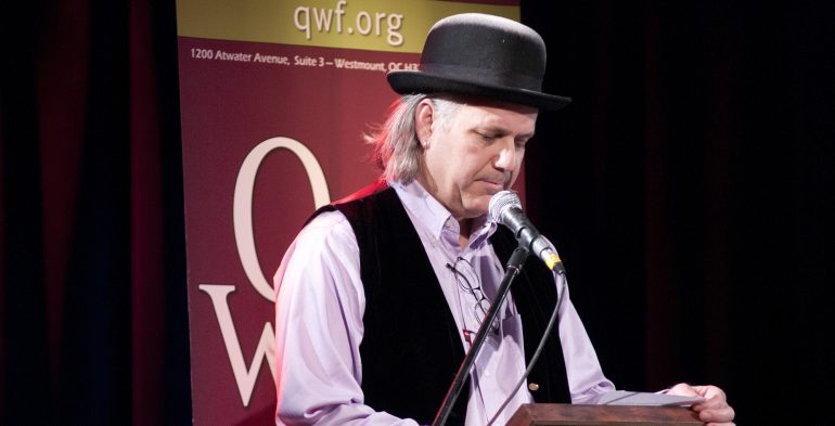 Man wearing bowler hat reading in microphone