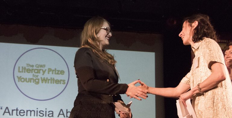 Two women shaking hands on a stage