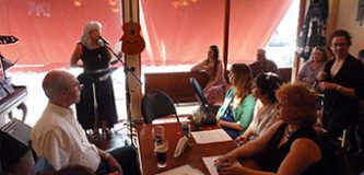 Woman reading at a microphone in front of an intimate audience