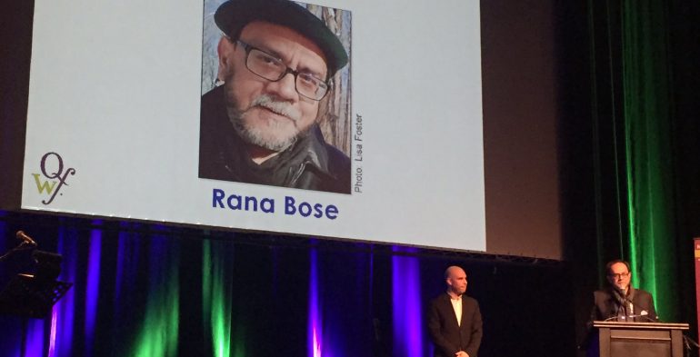 Middle aged man speaking into a a microphone on stage