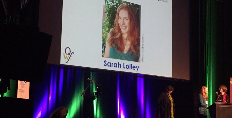 Young woman on stage with two others