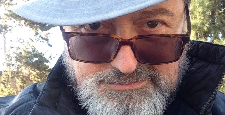 Bearded man wears a tilted hat and sunglasses